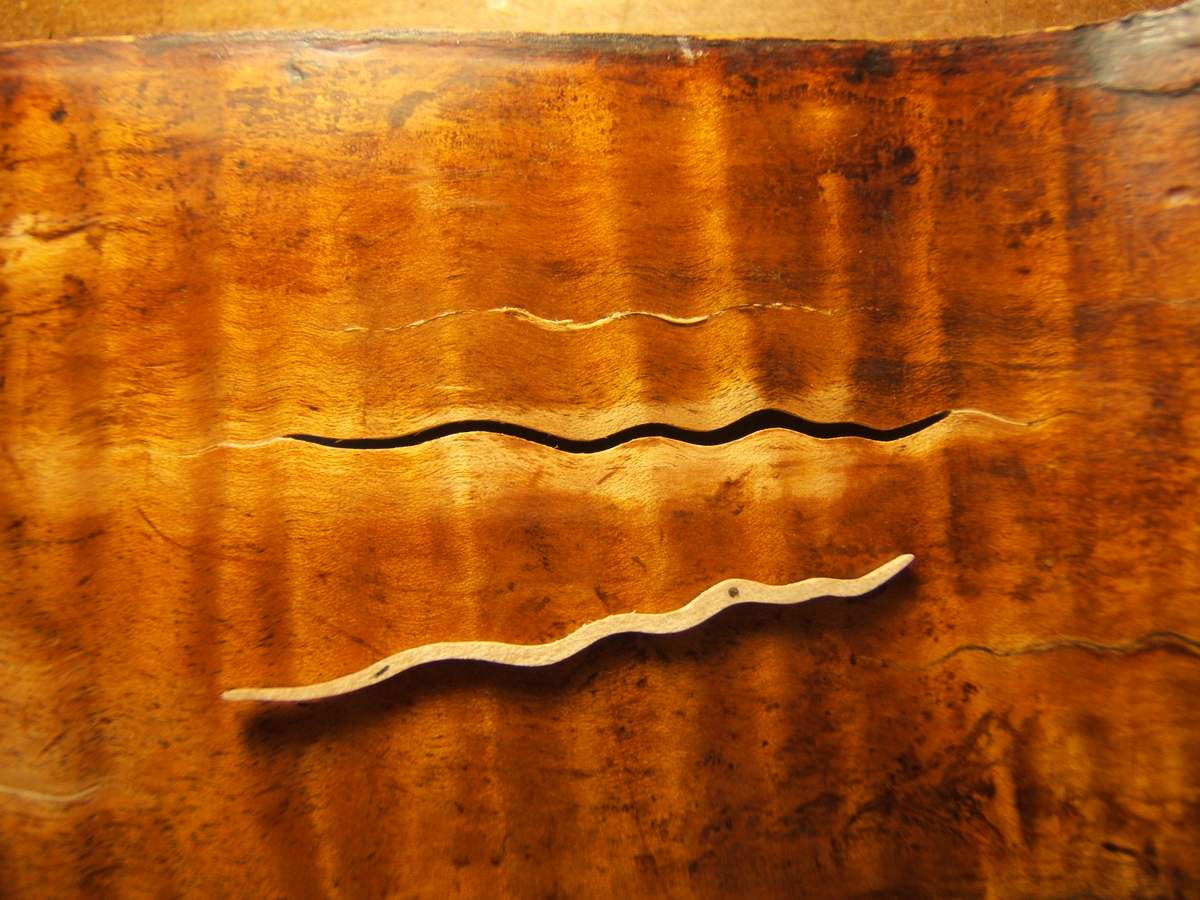 Crack in a flamed maple back closed with a fitted sliver of wood